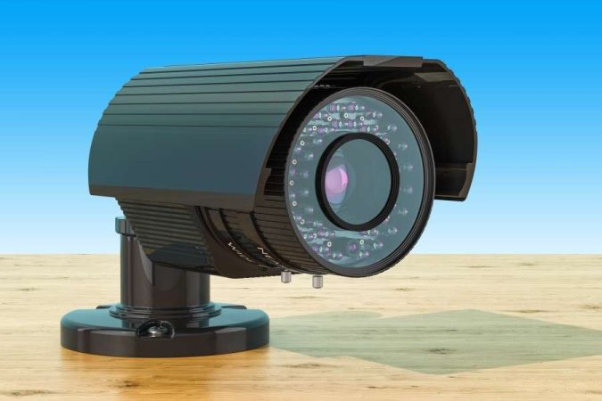 Un modèle 3D détaillé d'une caméra de surveillance noire posée sur une surface en bois.