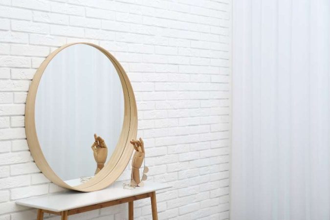 Un miroir rond épuré posé sur une console, idéal pour optimiser la décoration avec des miroirs et les petits espaces.