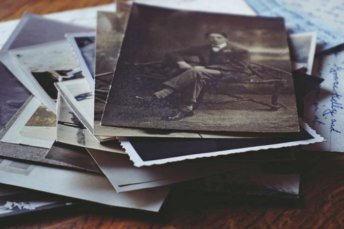 Un tas de vieilles photographies de famille vintage en noir et blanc éparpillées sur une table en bois.