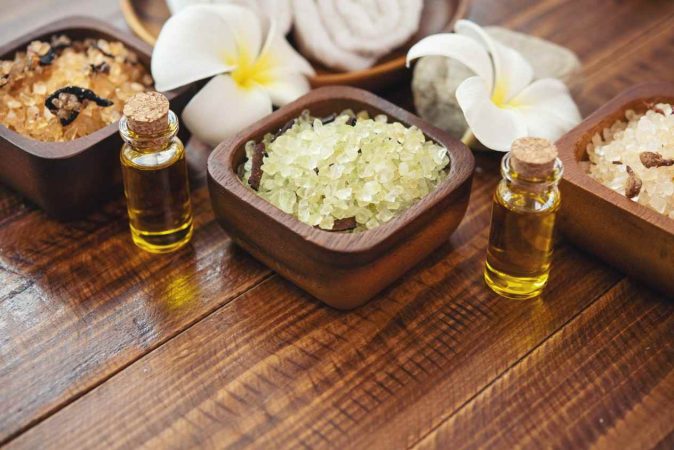 Flacons d'huiles essentielles et bols de sels de bain utilisés pour illustrer le massage ayurvédique abhyanga origines et bienfaits.