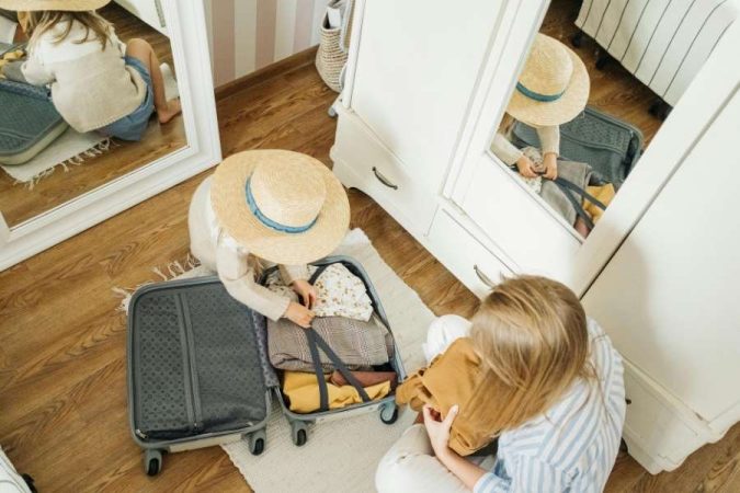 Une mère et sa fille préparent une valise lors de l'organisation des vacances en famille.