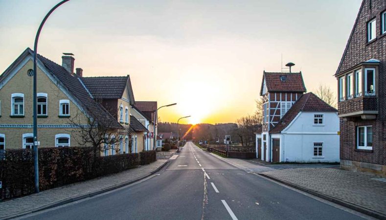 Rue paisible d'un village périurbain au coucher du soleil illustrant l'étalement urbain prix maison couronne.